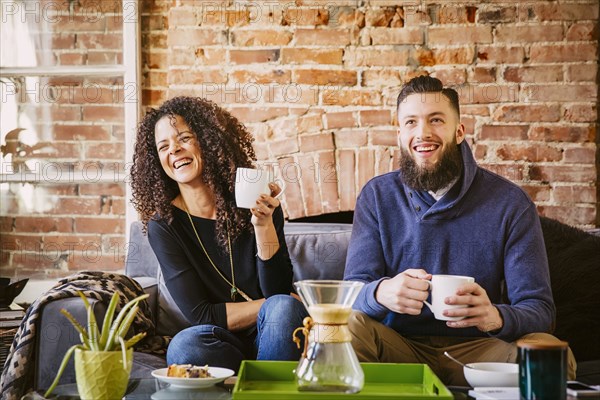 Couple drinking coffee on sofa in living room