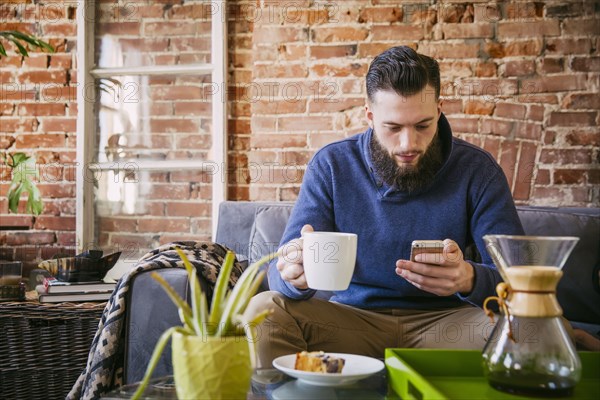 Caucasian man drinking coffee on sofa in living room