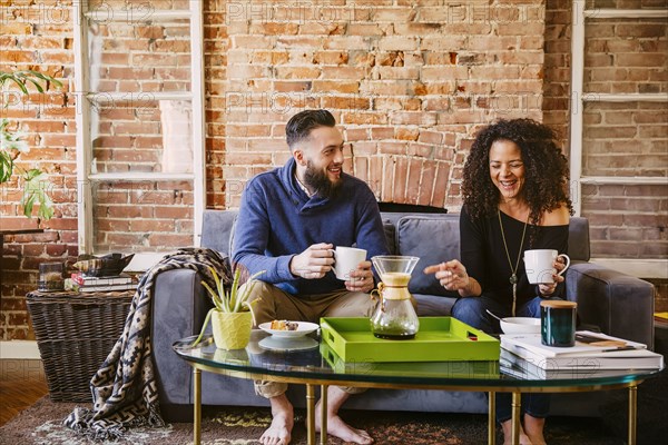 Couple drinking coffee on sofa in living room