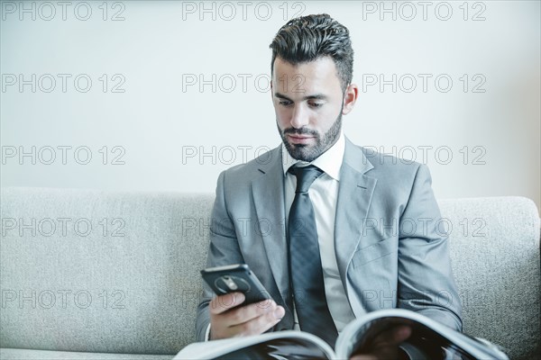 Businessman using cell phone on sofa