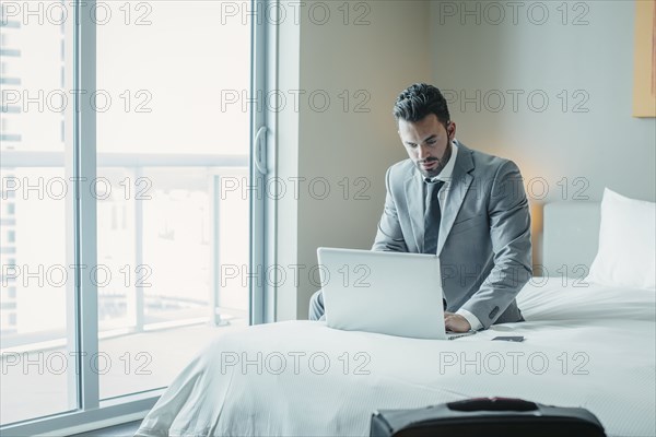 Businessman using laptop on hotel bed