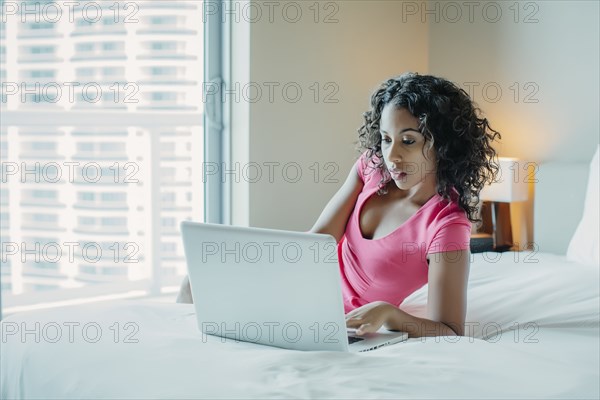 Woman using laptop on hotel bed