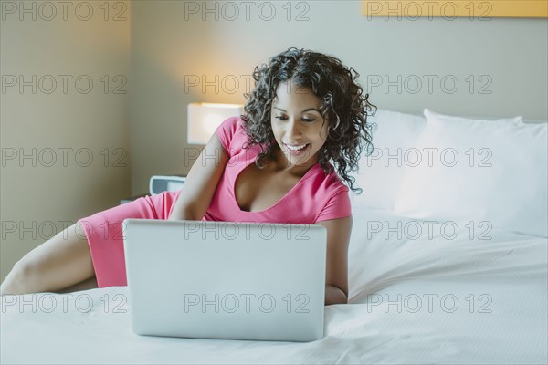 Woman using laptop on hotel bed