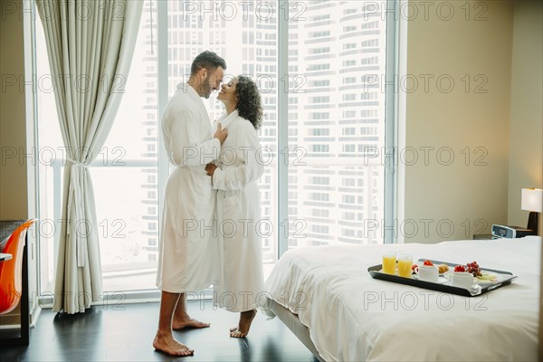 Couple hugging in bathrobes in hotel room