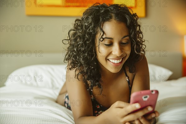 Close up of woman using cell phone on hotel bed