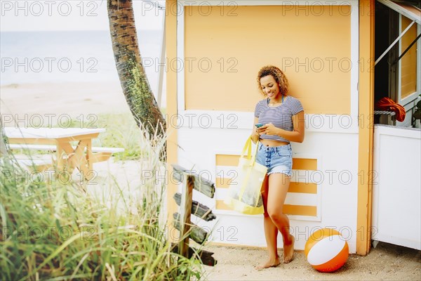 Mixed race teenager using cell phone on beach