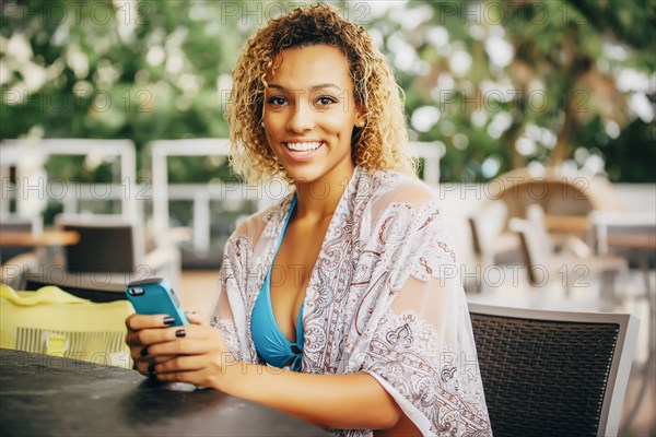 Mixed race teenager using cell phone at table