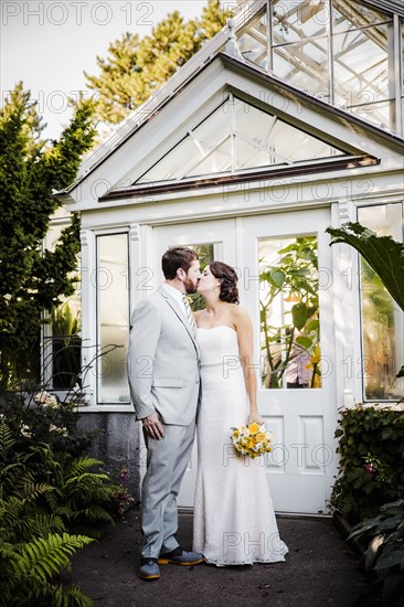 Caucasian bride and groom kissing in garden