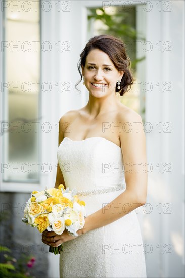 Caucasian bride holding bouquet in garden