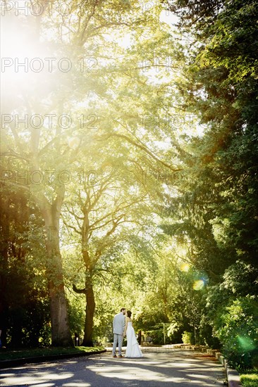 Caucasian bride and groom kissing on rural road