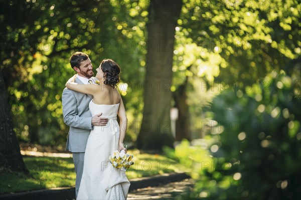 Caucasian bride and groom hugging on rural road