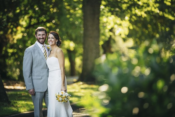 Caucasian bride and groom hugging on rural road