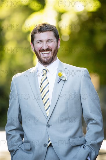 Caucasian groom laughing in garden