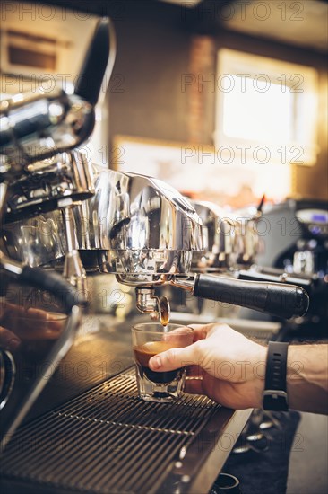 Caucasian barista pouring espresso shot in cafe