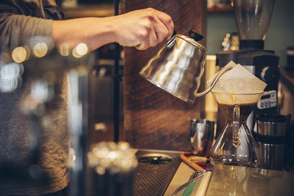 Caucasian barista pouring hot water over coffee in cafe