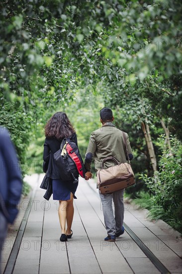 Couple walking on wooden walkway in park