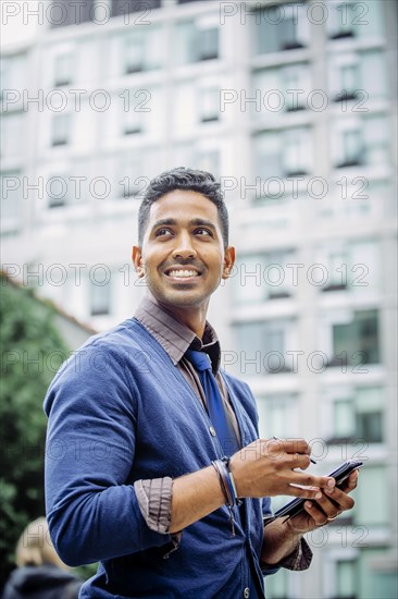 Indian businessman using cell phone outdoors