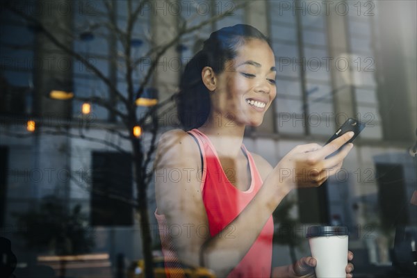 Mixed race woman using cell phone in cafe