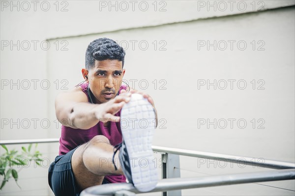 Indian man stretching on banister