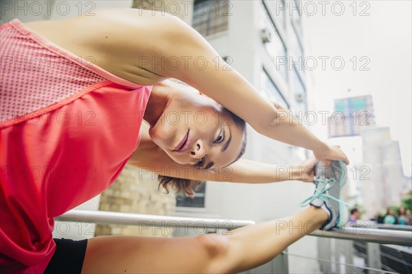 Mixed race athlete stretching on banister