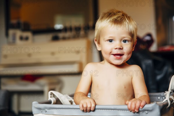 Mixed race boy sitting in laundry hamper