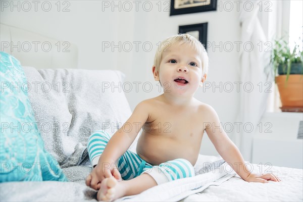 Mixed race boy sitting on bed