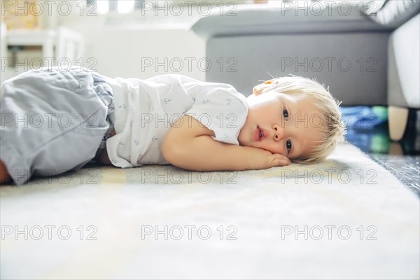 Mixed race boy laying on living room floor