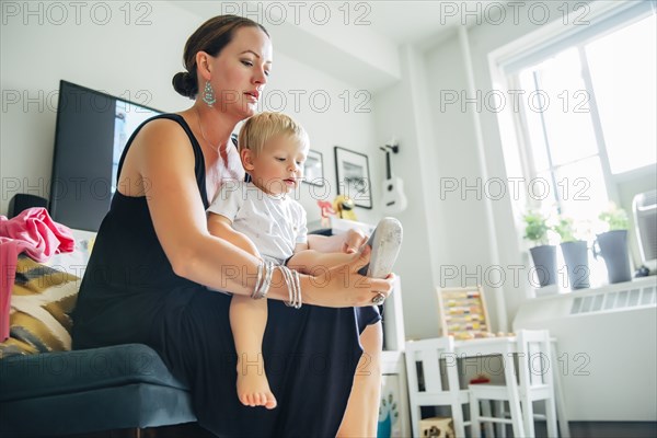 Mother helping son put on shoes in living room