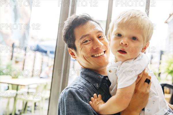 Smiling father holding son by window