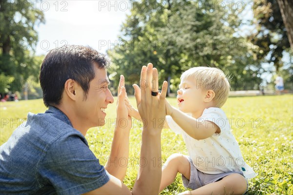 Father and son playing in grass in park