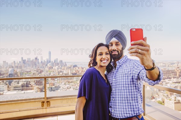 Indian couple taking selfie over New York cityscape