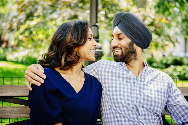 Indian couple hugging on bench in urban park