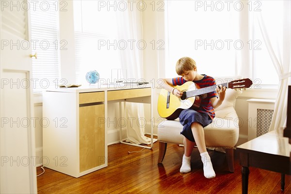 Caucasian boy playing guitar in living room