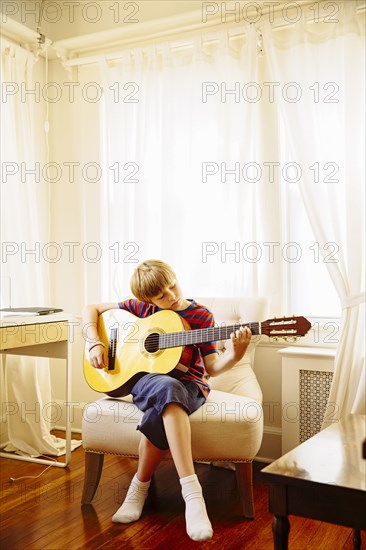 Caucasian boy playing guitar in living room