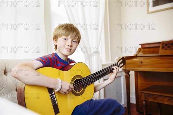 Caucasian boy playing guitar in living room
