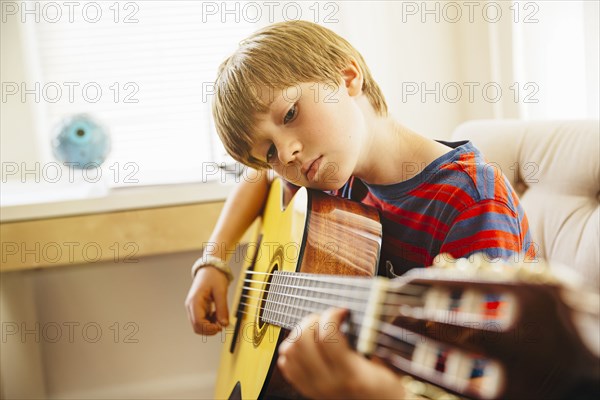 Caucasian boy playing guitar in living room