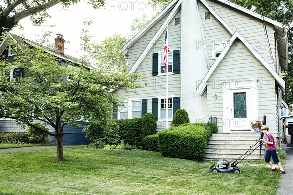 Caucasian boy mowing front lawn