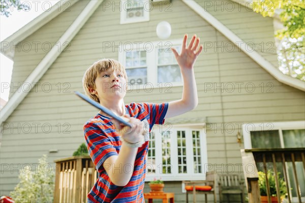 Caucasian boy playing table tennis in backyard