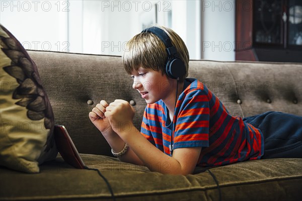 Caucasian boy using digital tablet on sofa