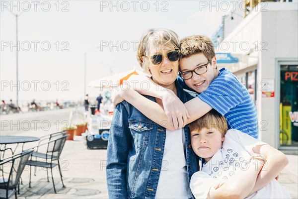 Caucasian grandmother and grandsons hugging in city