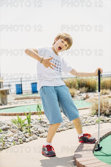 Caucasian boy playing miniature golf on course