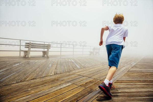 Caucasian boy running on wooden boardwalk