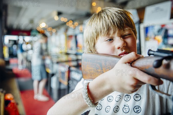 Caucasian boy aiming gun in arcade shooting game