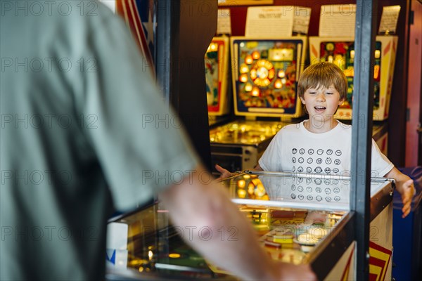 Caucasian father and son playing game in arcade