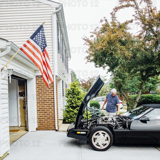 Caucasian man repairing car in driveway