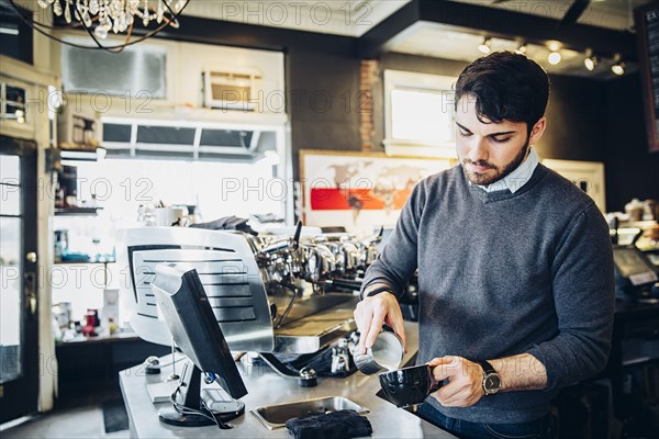 Caucasian barista making coffee in cafe