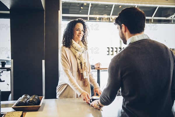 Barista serving customer coffee in cafe