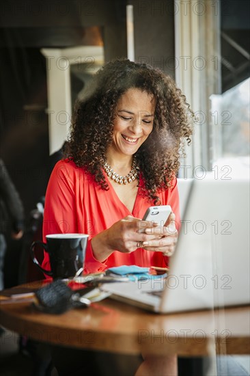 Businesswoman using cell phone in cafe