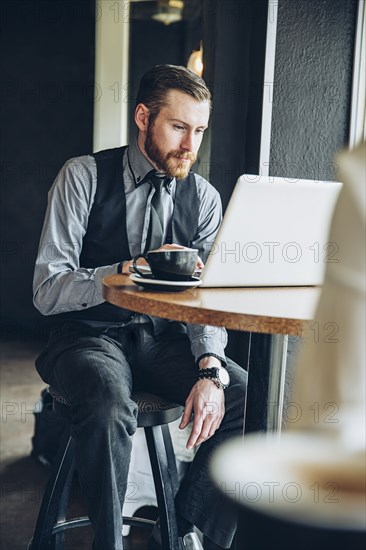 Caucasian businessman using laptop in cafe