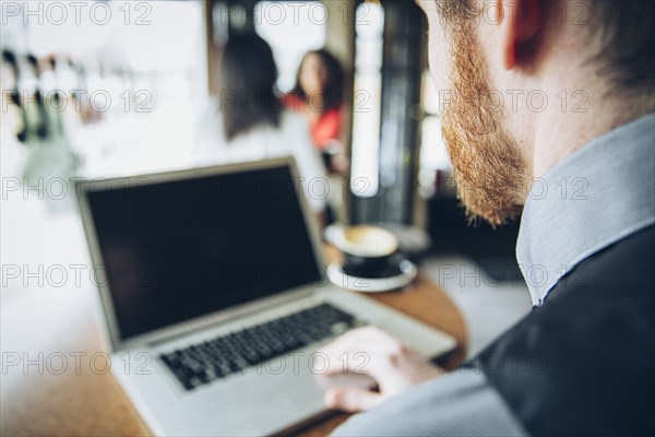 Caucasian businessman using laptop in cafe